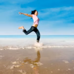full-length-woman-jumping-beach_1048944-14843165